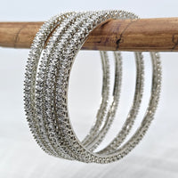 Silver bangles on a wooden stick against a light background