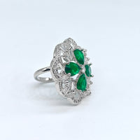 Silver ring with green gemstones on a white background