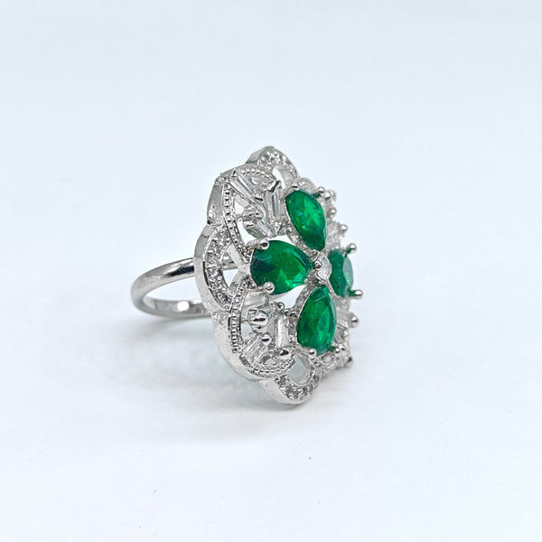 Silver ring with green gemstones on a white background