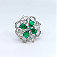 Silver brooch with green gemstones on a white background