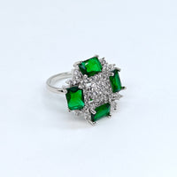 Silver ring with green gemstones on a white background