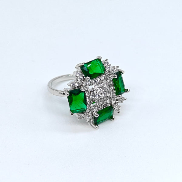 Silver ring with green gemstones on a white background