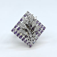 Silver brooch with purple gemstones on a white background
