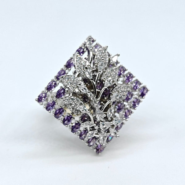 Silver brooch with purple gemstones on a white background