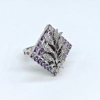 Silver ring with purple gemstones on a light gray background