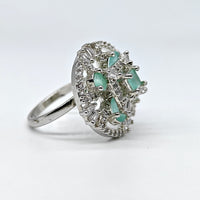 Silver ring with green gemstones on a white background