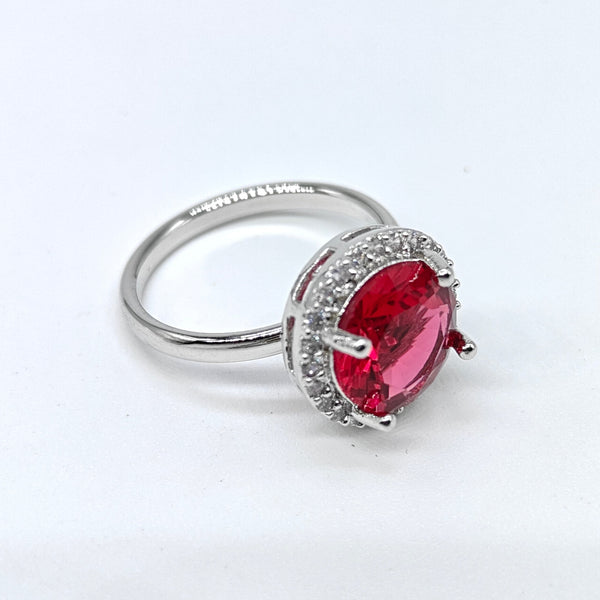Silver ring with a red gemstone on a white background
