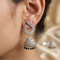Close-up of a silver earring with black accents worn by a person.