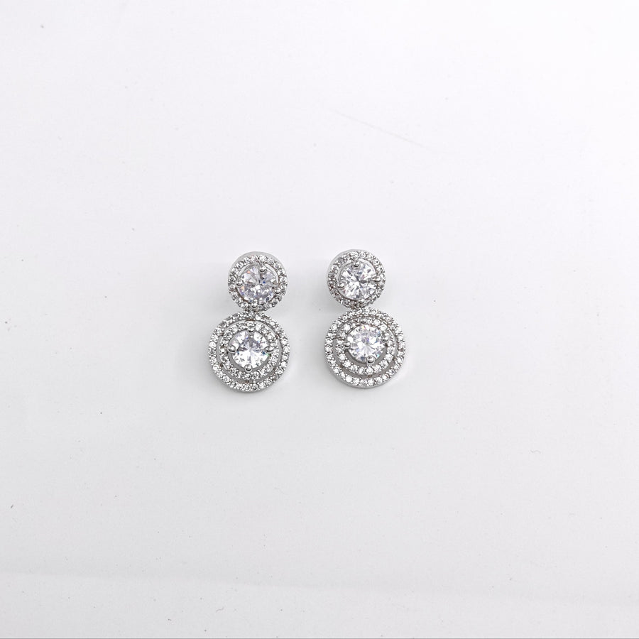 Pair of silver earrings with clear stones on a light gray background