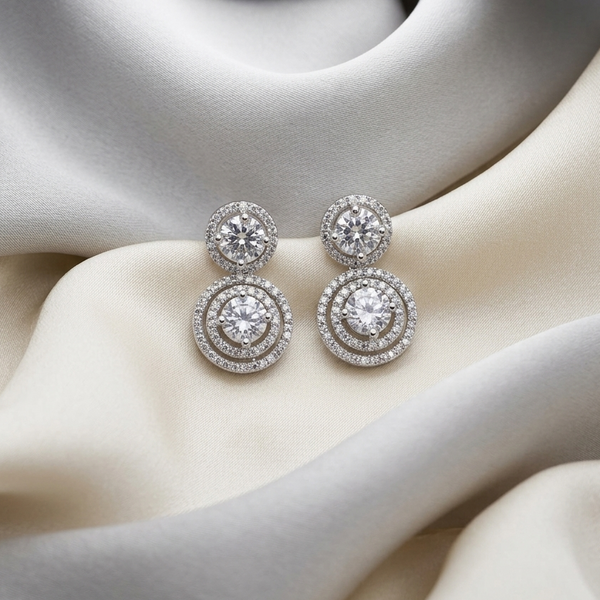 Pair of silver earrings with clear stones on a mannequin bust.
