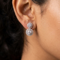 Close-up of a person wearing a pair of diamond earrings.