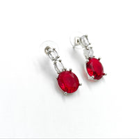 Pair of earrings with red gemstones on a white background