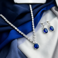 Jewelry set with necklace and earrings on a blue and white fabric background