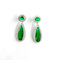 Pair of emerald green teardrop earrings with silver accents on a white background