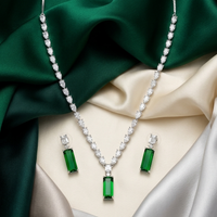 Jewelry set with emerald green gemstones on a fabric background